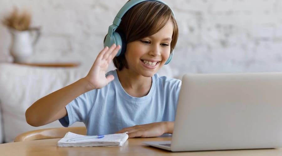 Criança sentada com laptop aprendendo inglês online com a escola de idiomas Berlitz.