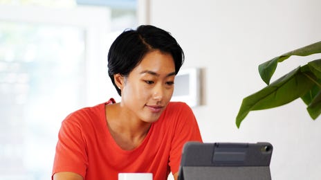 Mulher asiática vendo um conteúdo em um tablet.