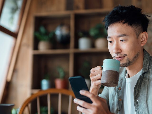 Homem tomando um café enquanto confere sua agenda no celular para as aulas do curso de japonês no RJ.