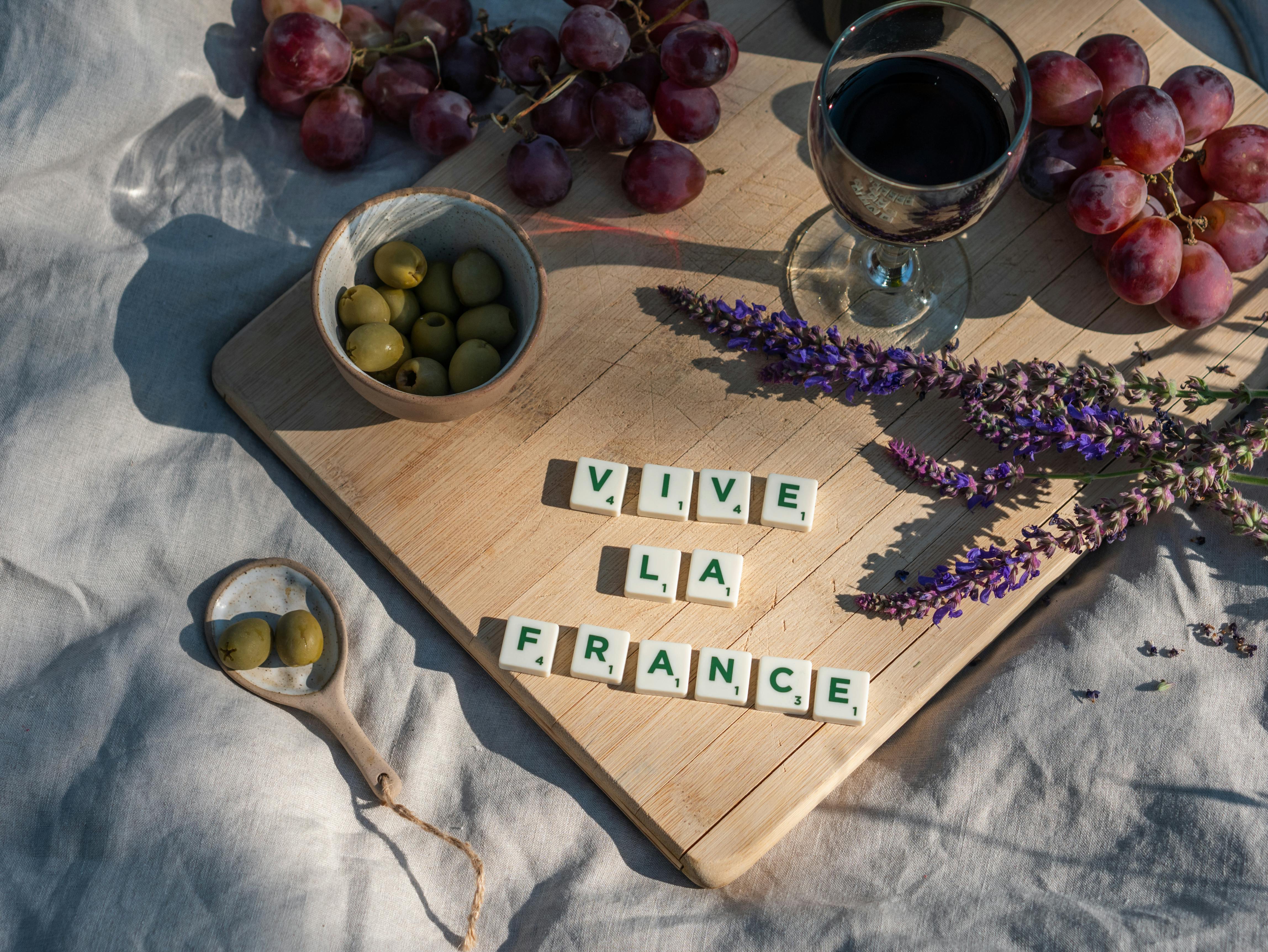 Vive La France numa tábua de madeira com taça de vinho, azeitonas e uvas para representar os restaurantes na França.