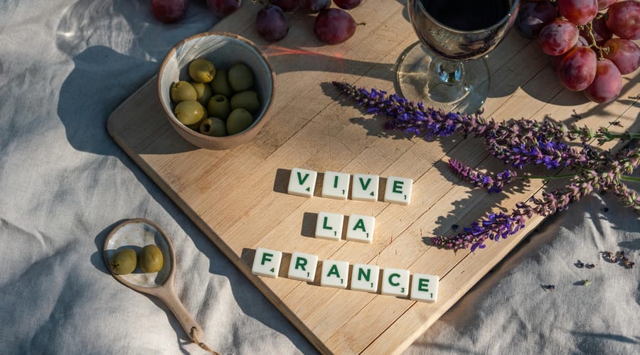 Vive La France numa tábua de madeira com taça de vinho, azeitonas e uvas para representar os restaurantes na França.