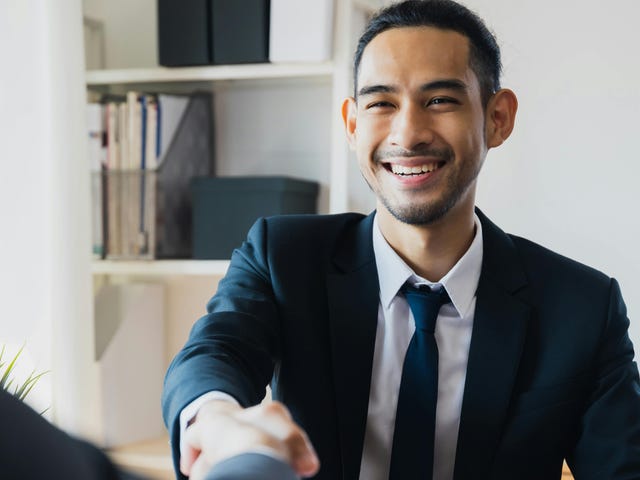 Homem apertando a mão de uma pessoa durante um processo de negociação.