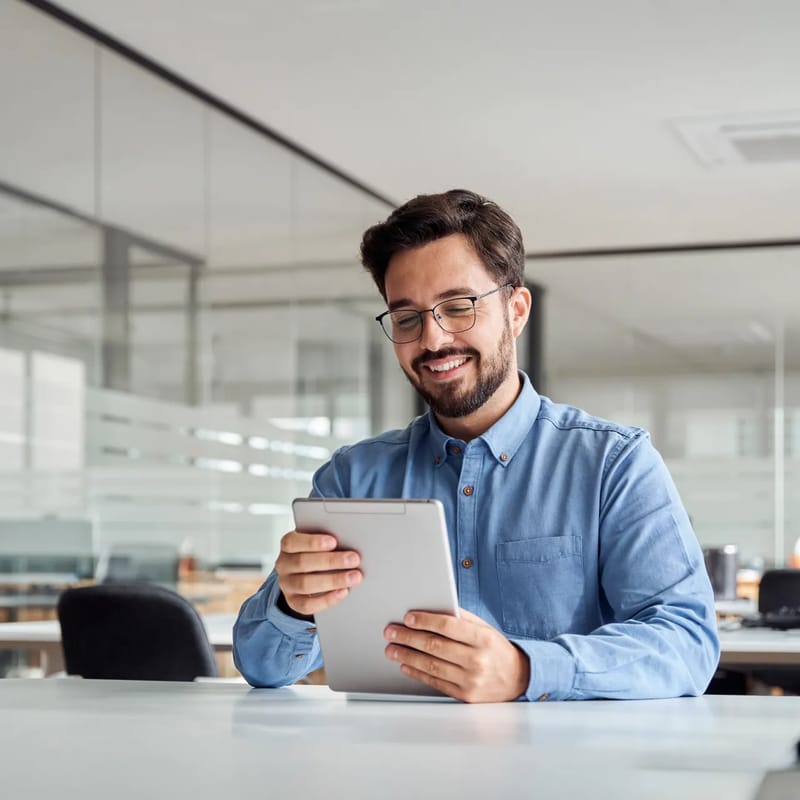 Homem segurando um tablet e lendo sobre os melhores cursos de espanhol online no Brasil em 2026.