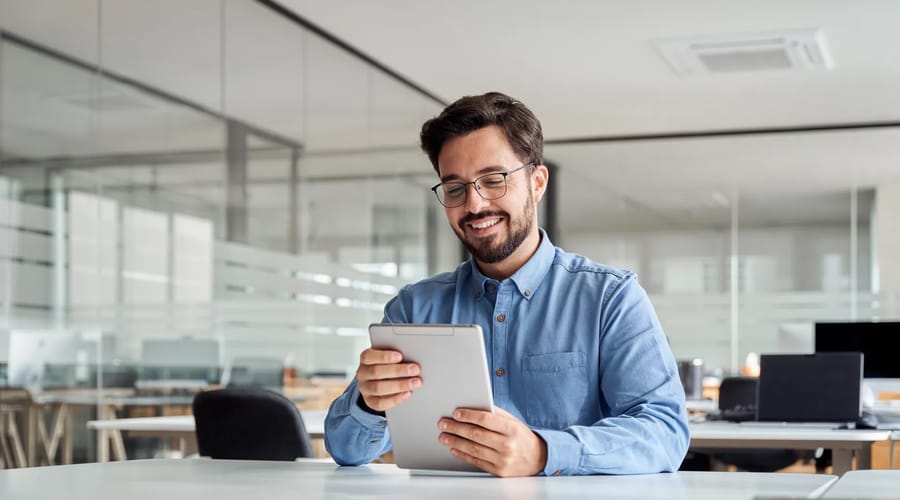 Homem segurando um tablet e lendo sobre os melhores cursos de espanhol online no Brasil em 2026.