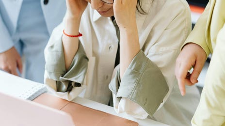 Mulher sendo pressionada por outros colaboradores e não conseguindo fazer sua gestão de estresse.