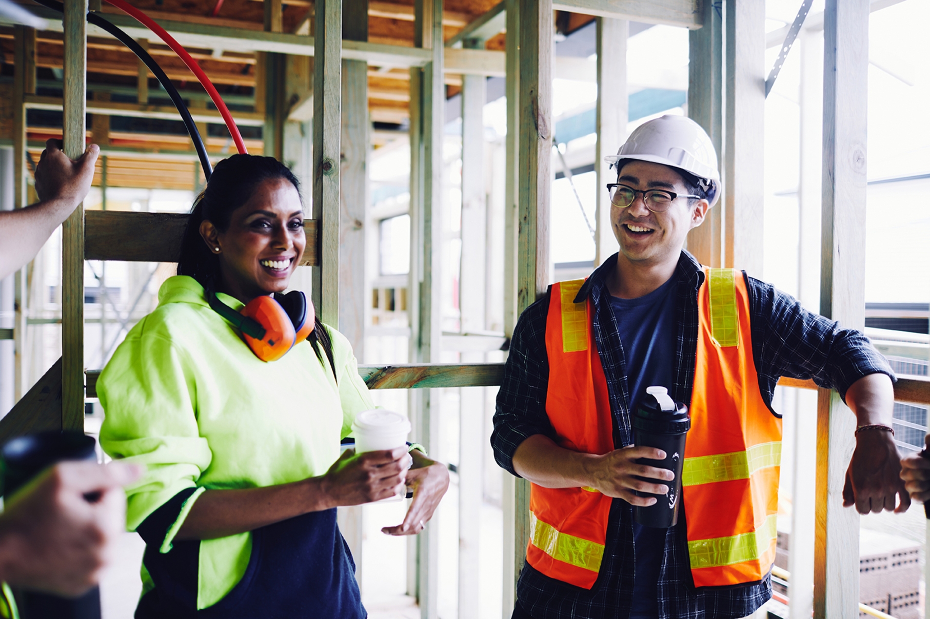 Dois engenheiros fazendo uma pausa na obra enquanto tomam um café e conversam sobre termos em inglês para engenheiros.