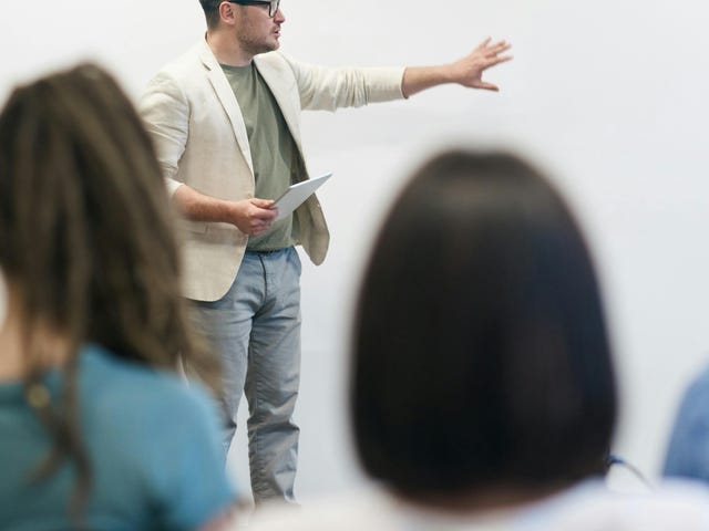 Homem realizando uma apresentação em inglês para uma turma.