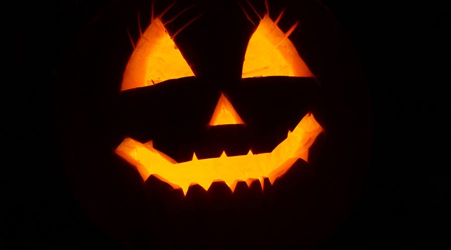Abóbora personalizada com um rosto e uma luz dentro da abóbora ressaltando o desenho. Conheça a origem do Halloween.