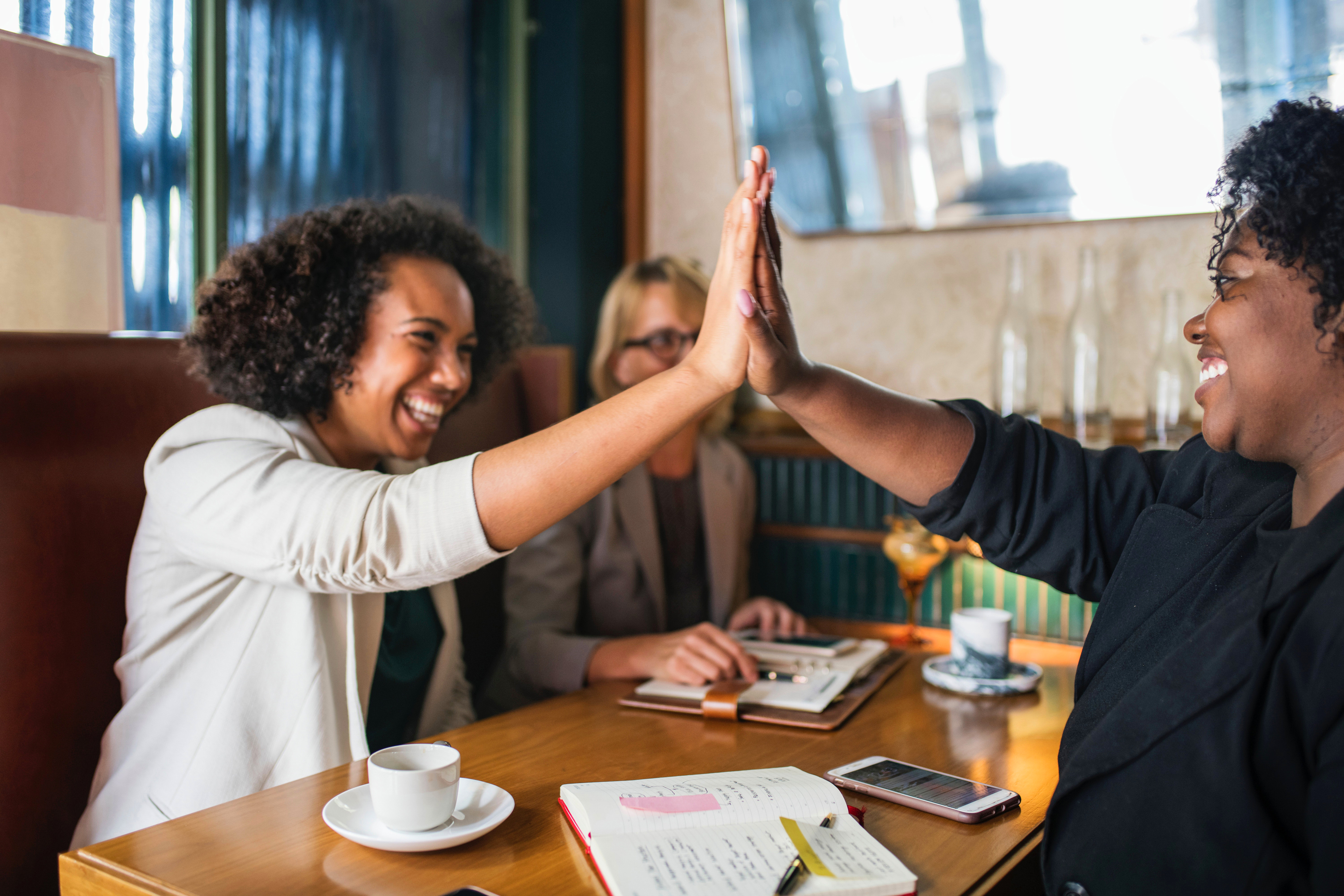 Pessoas fazendo um high five sentados em uma mesa de café.