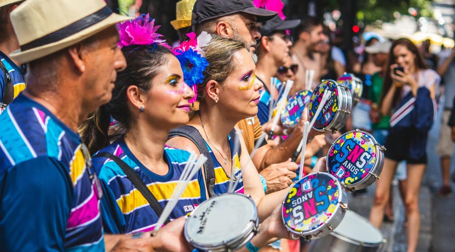 Grupo de foliões comemoram o Carnaval no Brasil tocando instrumentos.