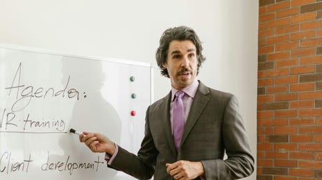 Homem demonstrando assertividade durante uma apresentação de agenda em um quadro branco.