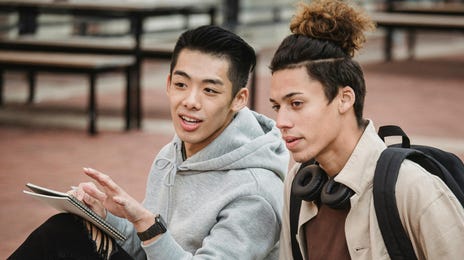 Dois alunos lendo um livro em francês no Rio para a prova do curso.