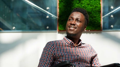 Homem negro em cadeiras de rodas após sair da prova de nível C2 do Telc.