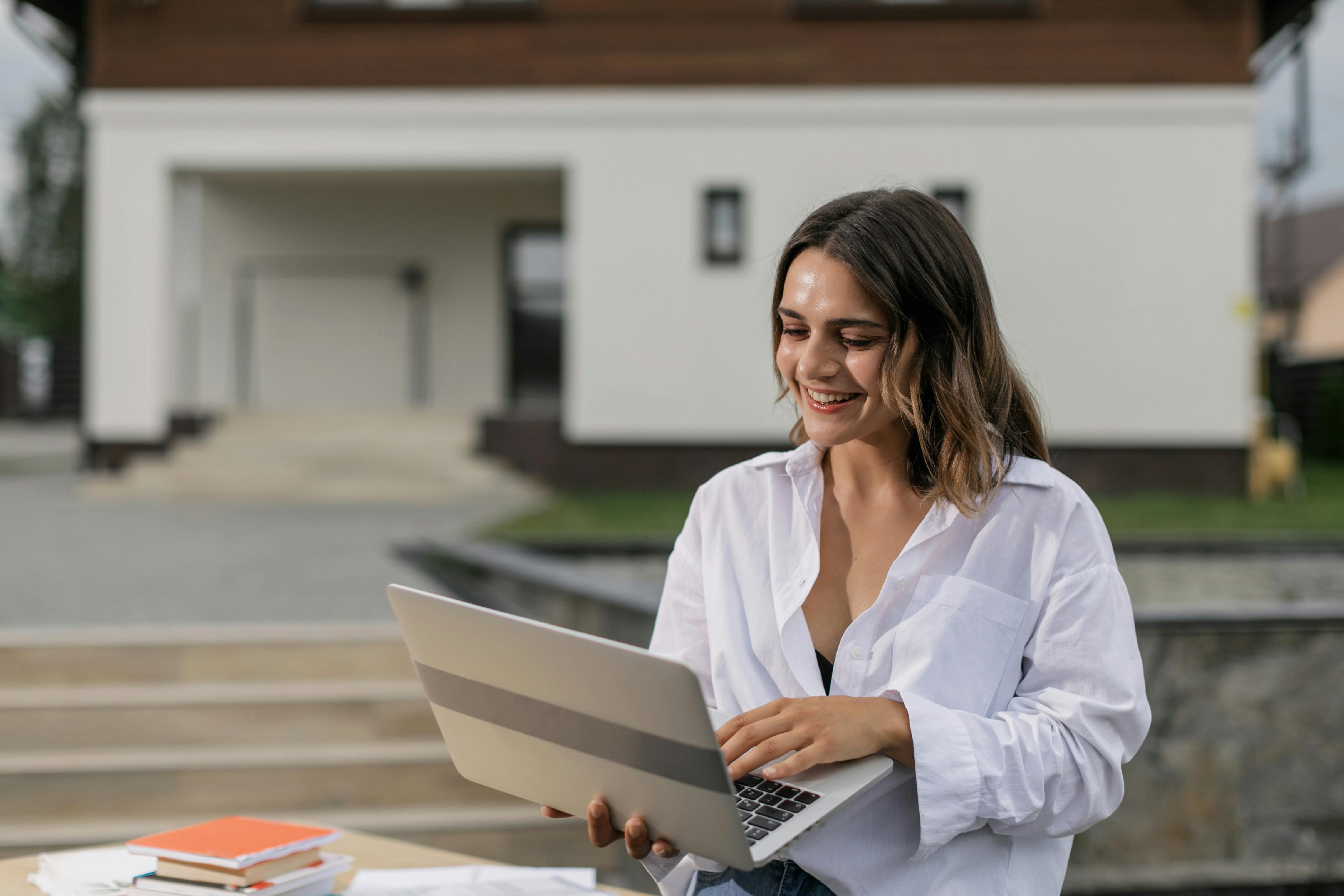 Mulher feliz enquanto estuda pelo computador com um curso de alemão online.