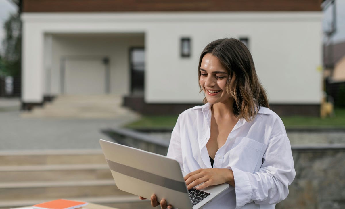 Mulher feliz enquanto estuda pelo computador com um curso de alemão online.