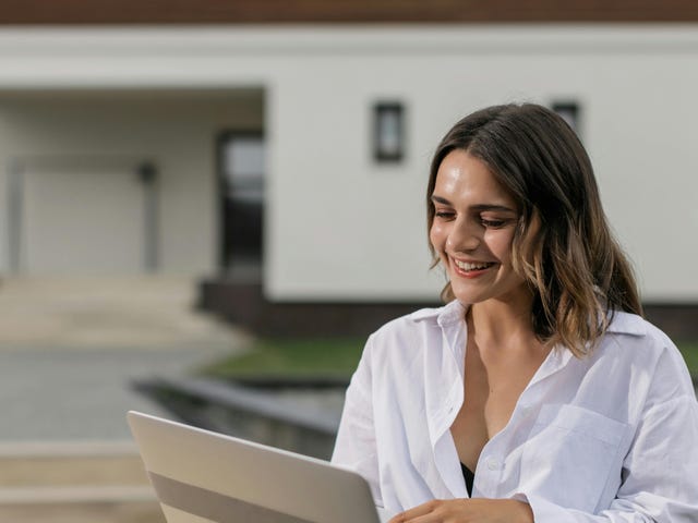 Mulher feliz enquanto estuda pelo computador com um curso de alemão online.