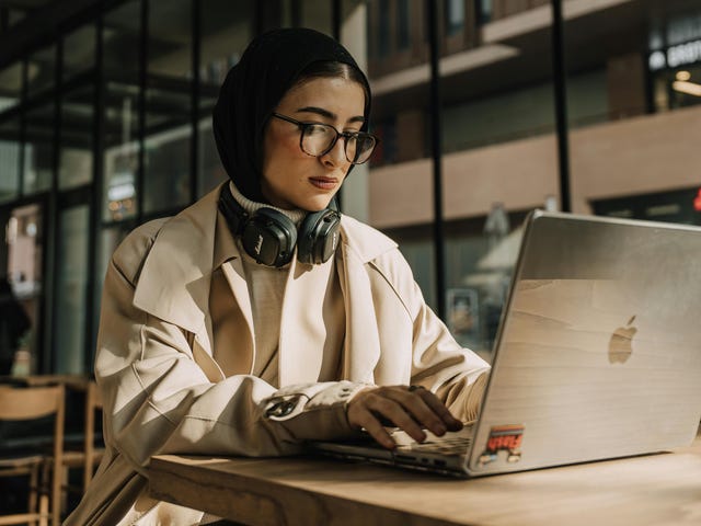 Mulher jovem estudando pelo computador com uma expressão séria.