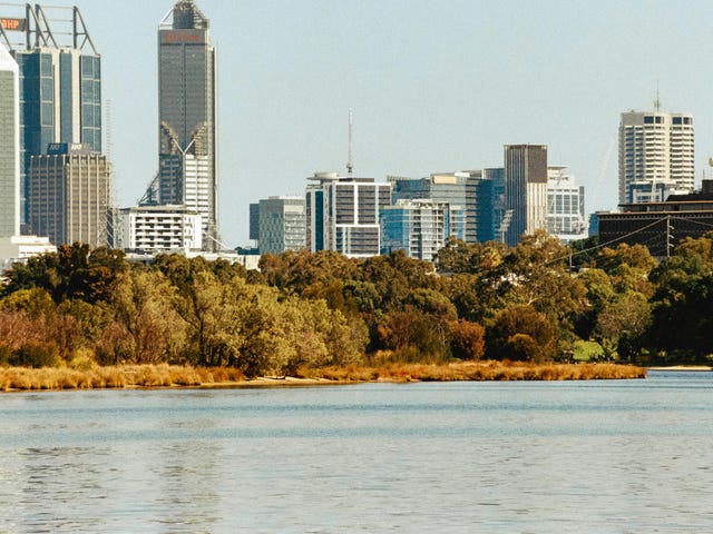 Vista da cidade de Perth, na Austrália, com bosques ao lado de um lago e edifícios.