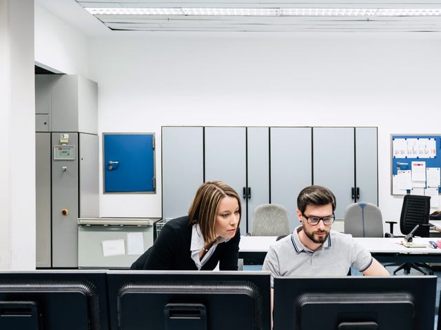 Duas pessoas da área de tecnologia aprendendo inglês em sala com computadores.