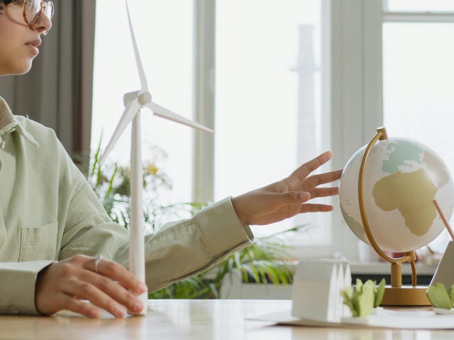 Mulher em sua mesa com a mão encostando um globo pensando sobre o impacto das alterações climáticas.
