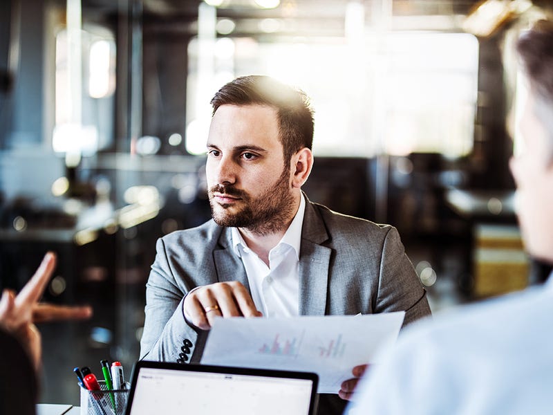Três colaboradores reunidos para analisar gráficos sobre o desempenho da administração estratégica das lideranças.