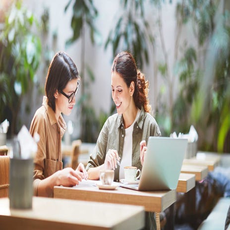 Duas mulheres tomando um café enquanto estudam para uma prova.