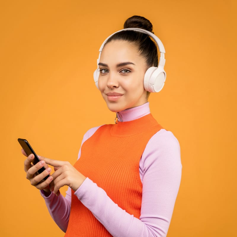 Mulher escutando áudio nos fones de ouvido para treinar o listening em inglês.