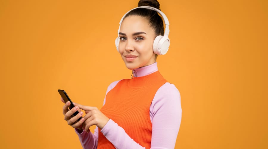 Mulher escutando áudio nos fones de ouvido para treinar o listening em inglês.