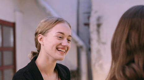 Mulher faz aulas de alemão online em grupo e conversa com colega de classe.