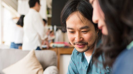 Mulher mostrando dados em um tablet com caneta para um colega.