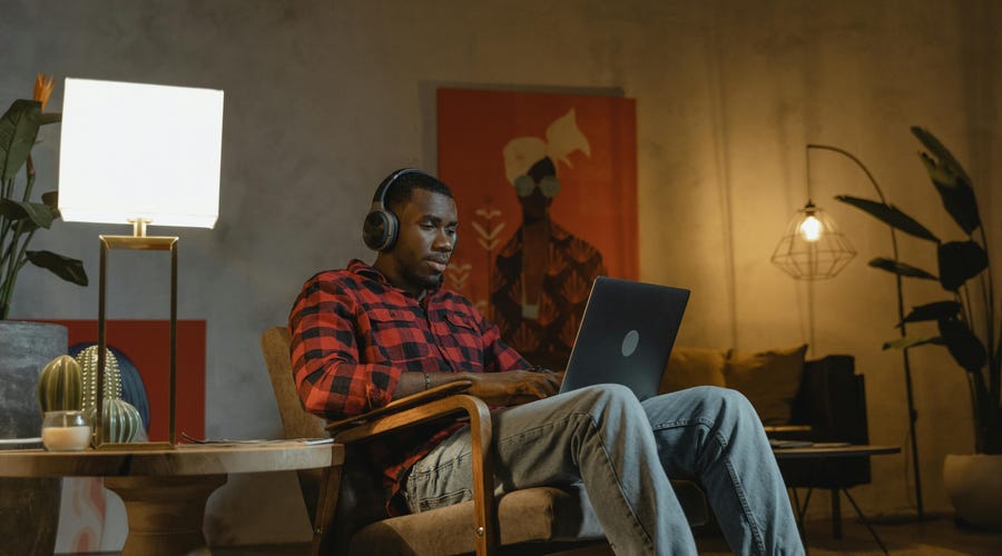 Homem negro estudando pelo computador enquanto utiliza o podcast como um dos recursos educacionais.