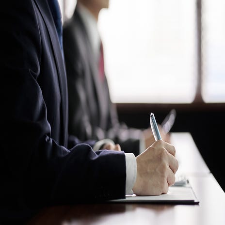 Advogado assina contrato com uma caneta em sala de reuniões.