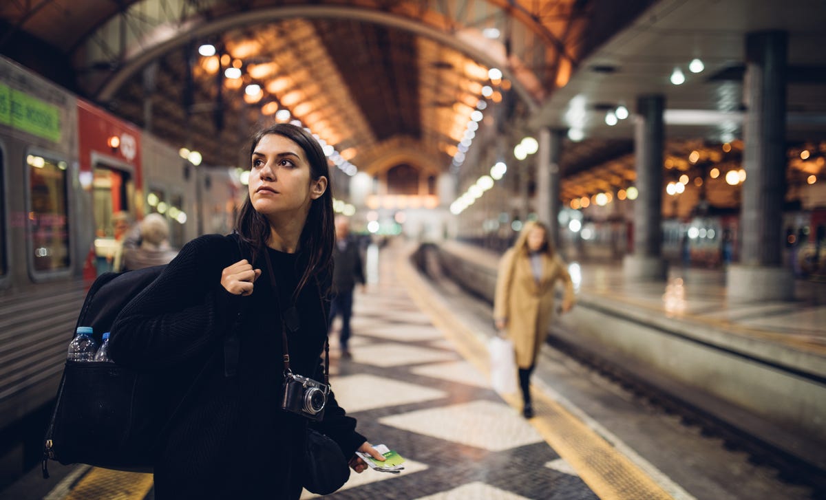 Mulher em uma estação de trem com uma câmera.