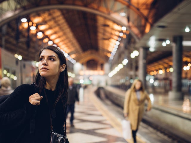 Mulher em uma estação de trem com uma câmera.