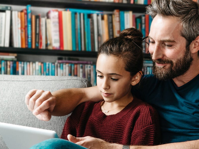 Pai ajuda filha a fazer aulas online na educação infantil