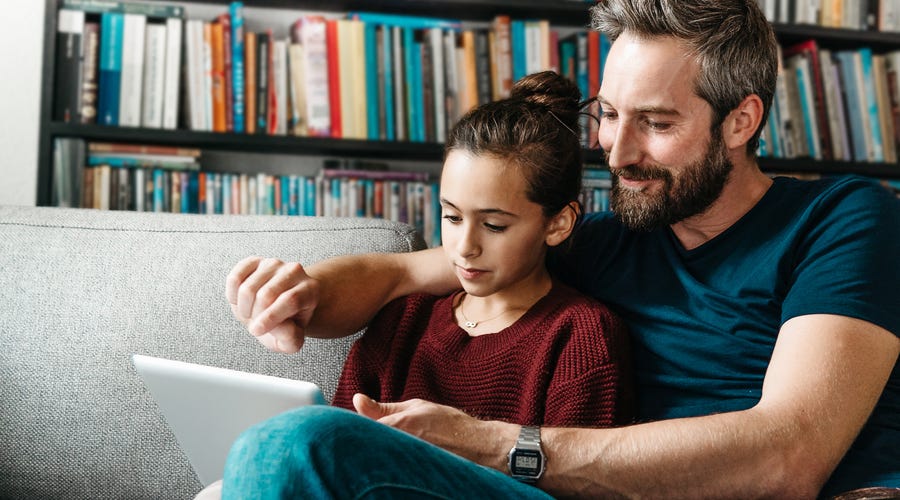 Pai ajuda filha a fazer aulas online na educação infantil