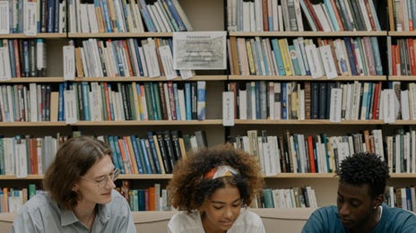 Três alunos estudando juntos em uma biblioteca para a prova de italiano no Rio.
