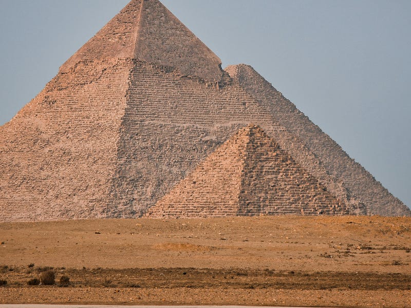 Mulher tomando café apoiada na mureta do segundo andar de sua casa.