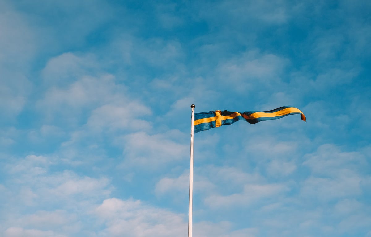 bandeira da Suécia no meio de um céu azul com nuvens