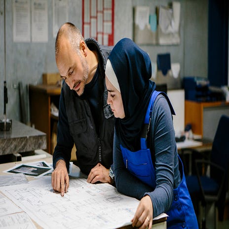 Dois colegas de trabalho analisando uma planta de um maquinário para o setor de mecânica industrial.