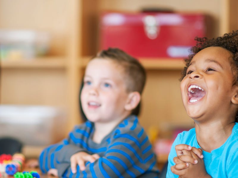 Criança rindo sobre algum assunto abordado na escola.