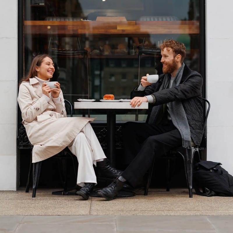 Homem e mulher sentados em uma mesa conversando sobre a cultura hispânica.