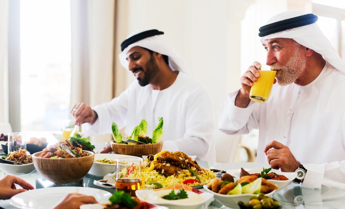 Pessoas com trajes típicos árabes comendo juntos.