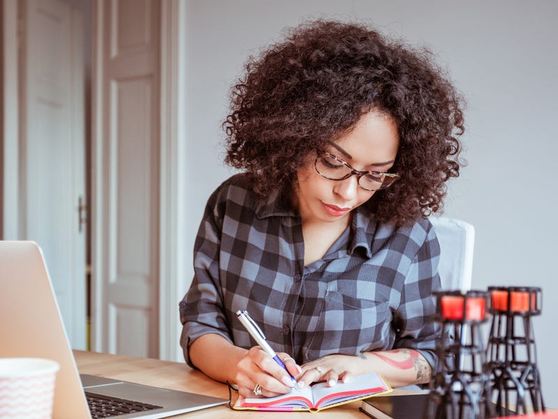 Mulher escreve diferentes formas de dizer obrigado em inglês no seu caderno