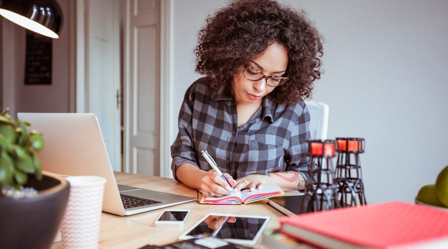 Mulher escreve diferentes formas de dizer obrigado em inglês no seu caderno