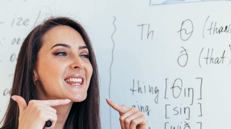 Mulher ao lado de uma lousa ensinando inglês na escola de idiomas Berlitz.