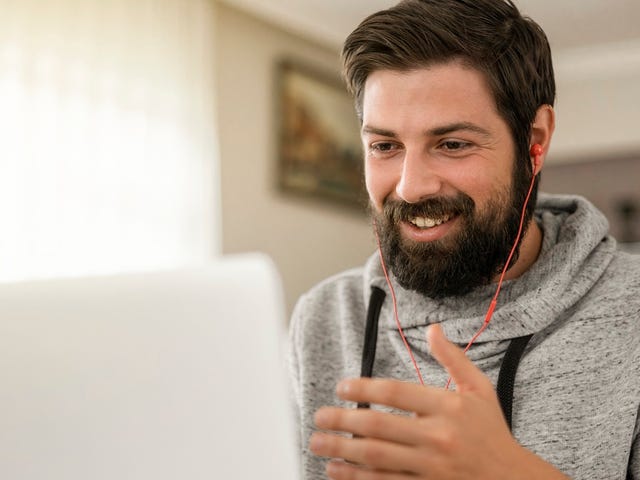 Homem feliz em uma chamada de vídeo com uma amiga para contar sobre o Telc C2.