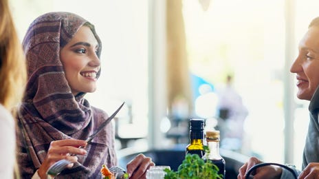 Mulheres utilizando hijab dividindo uma refeição.