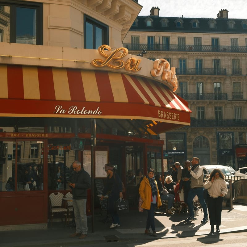 Fachada de um restaurante com pessoas na rua para representar os costumes da França.
