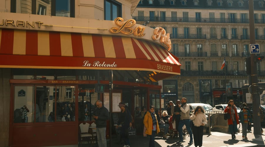 Fachada de um restaurante com pessoas na rua para representar os costumes da França.